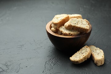 Traditional Italian almond biscuits (Cantucci) in bowl on black table, space for text