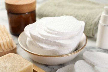 Cotton pads and beauty products on light table, closeup