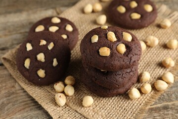 Tasty chocolate cookies with hazelnuts on wooden table, closeup