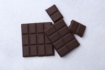 Pieces of delicious dark chocolate on light table, top view
