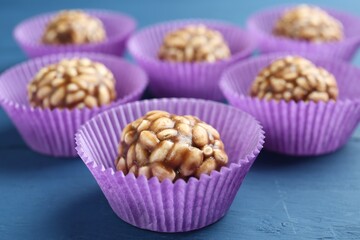 Tasty chocolate puffed rice balls on blue wooden table, closeup