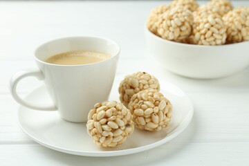 Tasty puffed rice balls and coffee on white wooden table, closeup