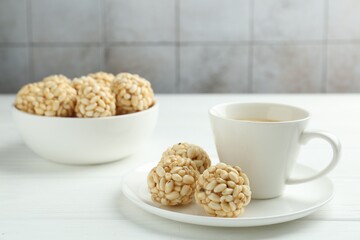 Tasty puffed rice balls and coffee on white wooden table, closeup