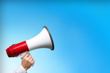 Human hand holding megaphone speaker on background