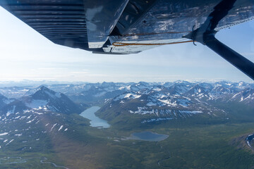 Aerial View of Snowy Mountain Range and Glacial Lake from Aircraft Window