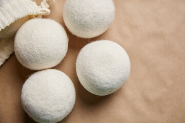 Wool dryer balls placed beside a cotton drawstring bag on a beige background, highlighting an eco-friendly laundry solution