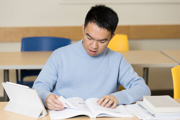 A man in a blue sweater sits comfortably at a desk reading