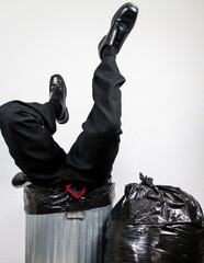 Businessman Stuck Upside Down in Trash Can Surrounded by Bags of Garbage. Over a Barrel. Concept of Being Sacked or Fired.