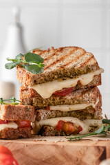 Grilled sandwich panini with mozzarella cheese, cherry tomatoes and pesto close up. Delicious breakfast or snack, traditional italian food