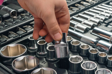 Child's hand picking up socket wrench head from tool kit