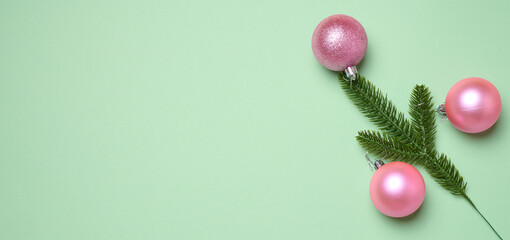 Shiny pink balls and green fir branches on green background, Christmas background