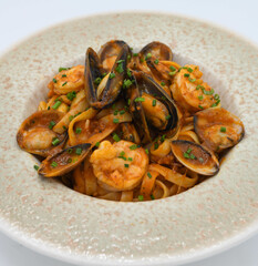 Un plato de pasta con marisco, almejas, mejillones y gambas, y salsa de tomate.