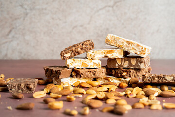 A close-up view of assorted nougat bars, featuring layers of chocolate, almonds, and peanuts...