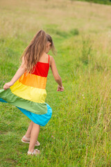 Fototapeta premium happy girl in a rainbow dress on the field