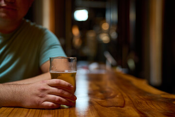 Close-up of a hand with a glass of beer on the bar