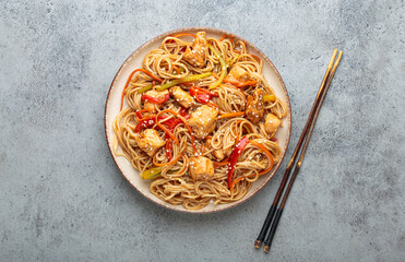 Udon noodles stir fried with chicken meat, carrots, bell peppers and other vegetables are served on...