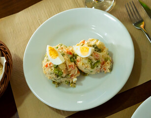 Ensalada rusa - salad with potatoes, tuna, green pea, olives and egg in a plate