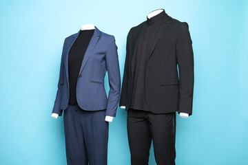 Female and male mannequins with stylish suits on light blue background