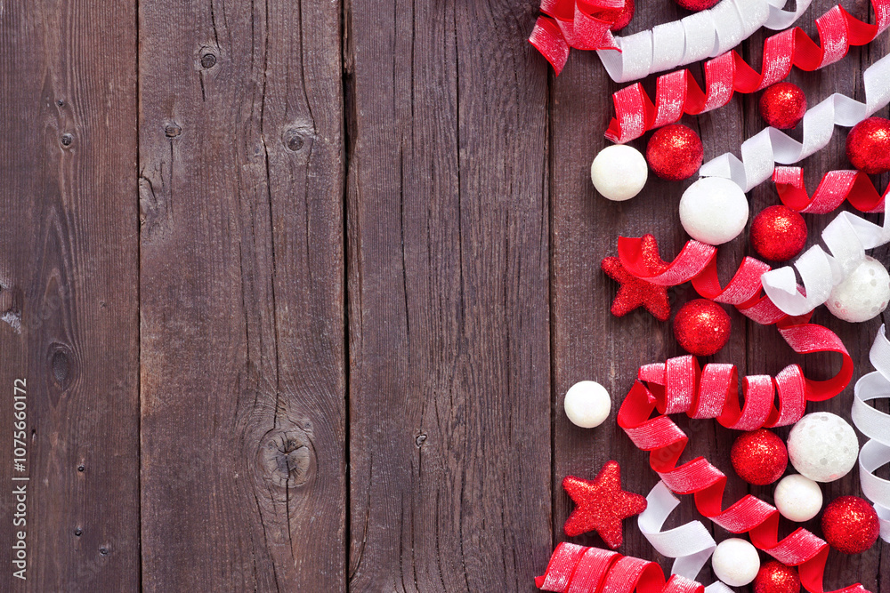 Poster christmas side border of red and white baubles and curly ribbon. top view on a dark wood background 