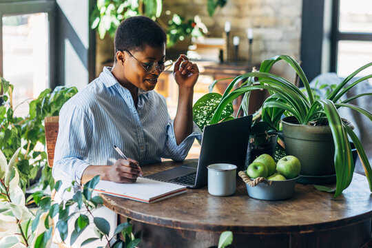 Cheerful healthy African American woman with laptop at home or in modern green office. Concept of video call, freelance job, studying remotely, learning, teaching languages, international education