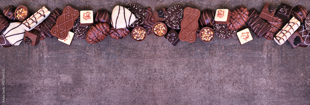 Poster chocolate top border with an assortment of fine, luxurious sweets. top view on a dark stone banner b