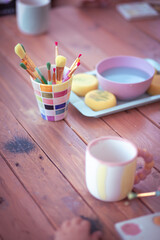 Many painting brushes in a pot while painting a mug on a wooden table