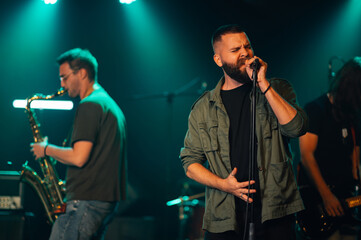 Singer performing with band on stage during concert