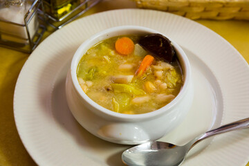 Traditional Catalan escudella served in ceramic soup bowl with slice of black botifarra..