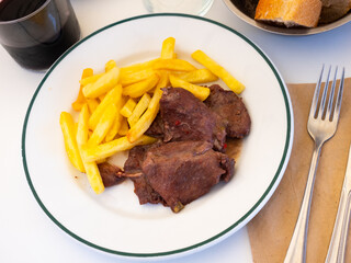Spanish Secreto de cerdo - fried pork in red, served with french fries