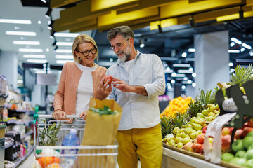 Senior couple choosing fresh produce at grocery store