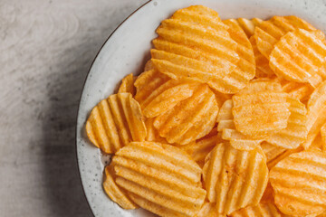 Crispy potato chips on plate on kitchen table. Top view.