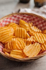 Crispy potato chips in basket on kitchen table.