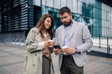 Business people talking and using smartphone outdoors during coffee break