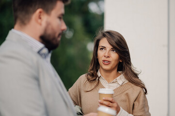 Businesswoman holding coffee cup talking to businessman outdoors