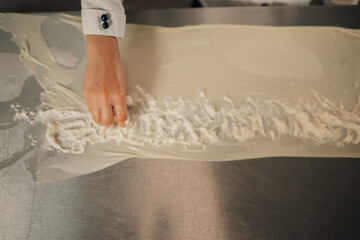 Hand meticulously spreading filling on a sheet of dough in kitchen