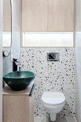Modern bathroom in a modern style. Ceramic green bathroom sink on a cabinet with tao and pattern tile on the wall with toilet in interior of washroom. Stylish home. Vertical.