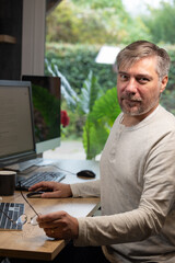 portrait d'un employé de bureau ou d'un homme d'affaires qui est assis à son bureau devant son ordinateur il est souriant et sympathique. Il est heureux de travailler chez lui à distance