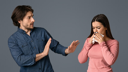 Virus Spread. Concerned young man keeping distance with his sick girlfriend, making pushing away gesture with hands, scared of coronavirus