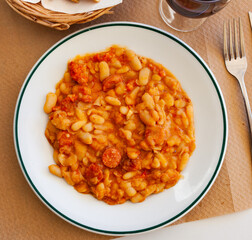 Appetizing braised beans with chorizo sausage pieces closeup