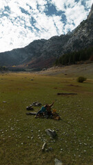 Young couple with two dogs - German and Australian shepherds traveling in Prokletije Mountains, Montenegro. Aerial top view. Hiking in the mountains in the autumn season. Dry Ropojana lake.