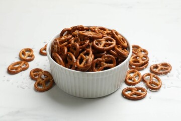 Tasty pretzel crackers with salt on white table, closeup