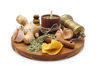 Herbal antiviral candle in clay pot between natural ingredients: beeswax, garlic, fresh ginger and dried eucalyptus leaf on round board isolated on white. Aromatherapy and alternative medicine.