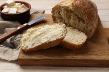 Fresh bread with butter on light wooden table, closeup