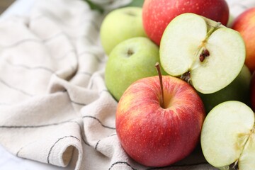 Different ripe whole and cut apples on towel, closeup