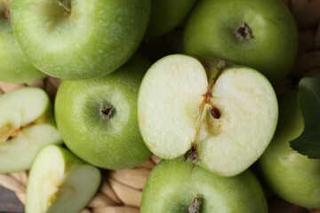 Whole and cut green apples on wicker mat, closeup