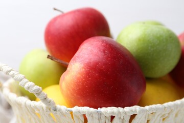 Different ripe whole apples in basket, closeup