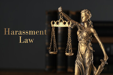 Harassment law. Statue of Lady Justice and books on dark background