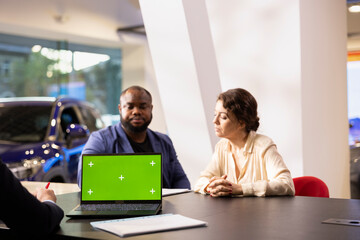 Showroom worker answering questions in car dealership during test drive using isolated screen laptop . Sales executive offering advice to clients in search of new vehicle using chroma key notebook