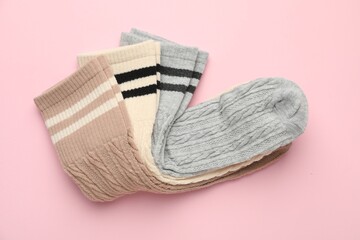 Different comfortable socks on light pink background, top view