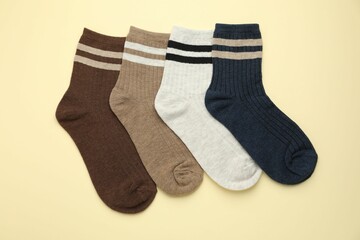 Different comfortable socks on beige background, flat lay